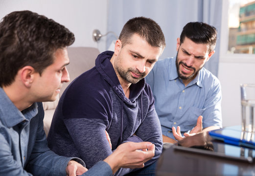 Three anxious men discussing on sofa