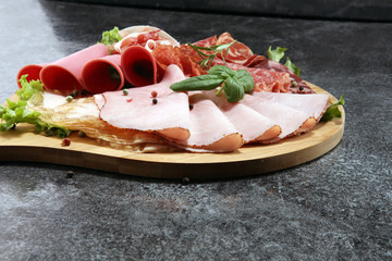 Food tray with delicious salami, pieces of sliced ham, sausage and salad. Meat platter with selection.