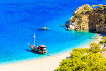 Fototapeta na wymiar Tourist boat anchoring at beautiful Apella beach on Karpathos island, Greece