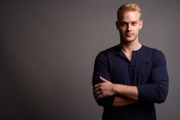 Young handsome man with blond hair against gray background