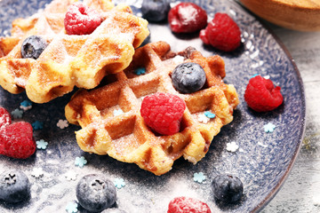 waffles with fresh blueberries, sugar and raspberries.
