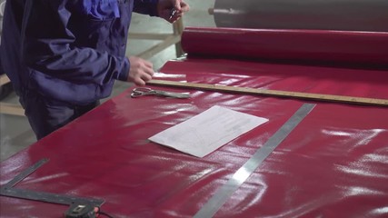 man makes the cutting of a plastic awning tent