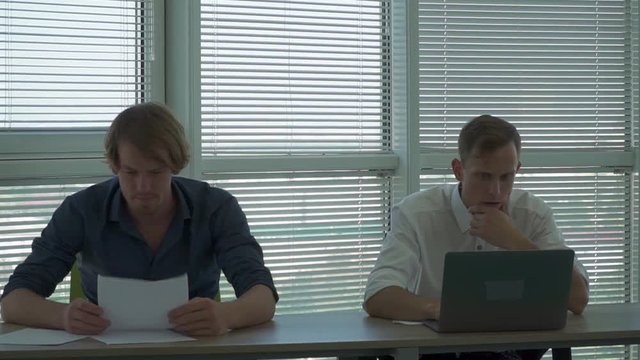 Two thinkful men sit at the table in the office