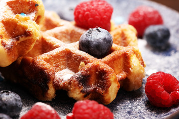 waffles with fresh blueberries, sugar and raspberries.