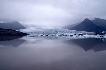 A moody photo of a glacier reaching down to the lake at its feet. 