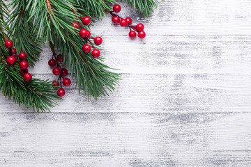 Christmas background with tree branches and holly berries. White wooden table. Top view. Copy space