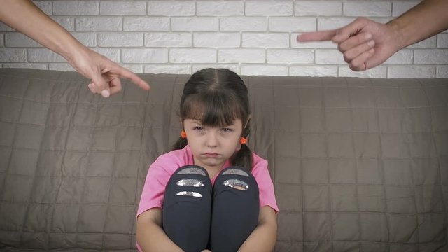 Parents scold the child. Sad little girl being scolded by parents.