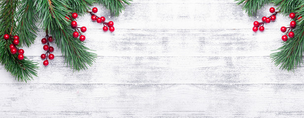 Christmas background with tree branches and holly berries. White wooden table. Top view. Copy space