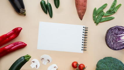 Open Notebook and Fresh Vegetables Background. Healthy food.