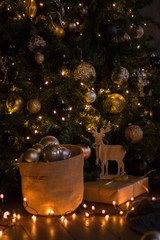 winter decor: Christmas tree, gifts in craft paper, wooden DIY deer, garland, golden and white balls. Selected focus