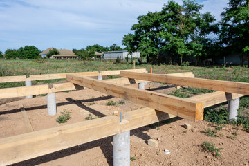 Pine wooden frame house foundation on concrete piles, construction site. Construction stages of the...