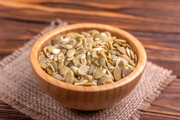 Fresh pumpkin seeds in wooden bowl with burlap napkin