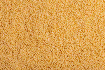 Yellow raw couscous grain background. Close up