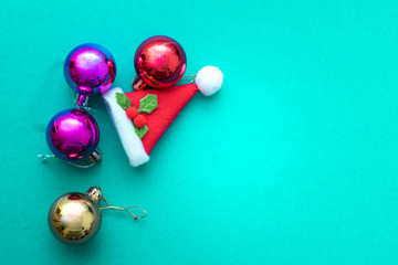 Fototapeta na wymiar Christmas ornament balls and santa hat on green background.