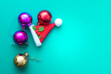 Christmas ornament balls and santa hat on green background.