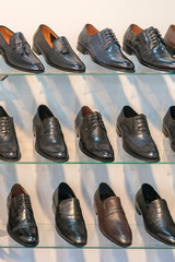 Men's leather shoes on the shelf in the store. Racks in the store of clothes and accessories. Shelves with stylish men's shoes. Many classic shoes and boots. vertical photo