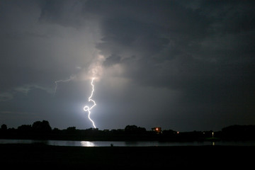 Naklejka na ściany i meble A lightningbolt with curl strikes down near a river in The Netherlands