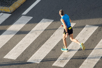 Athlete running man. Male runner passing crosswalk