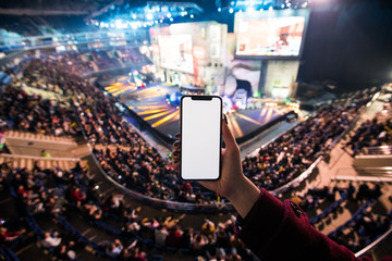Kobiet ręki używać cyfrowego zastosowanie na mobilnym mądrze telefonie przy esport wydarzeniem przy dużą areną. Skopiuj miejsce - 232185673
