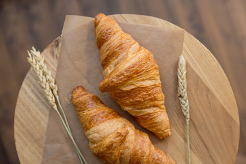 Breakfast. Croissants with wheat ears at baking paper on dark background