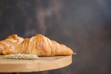 Breakfast. Croissants with wheat ears at baking paper on dark background
