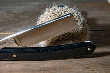 straight razor with shaving brush on rustic wood