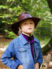 Caucasian schoolgirl in cowboy hat walking in the forest