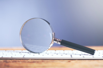 Magnifying glass lying on computer keyboard