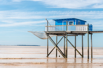 une cabane de pêcheur bleue sur pilotis au dessus d'une mer  marron