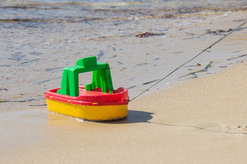 A colourful boat toy on sand