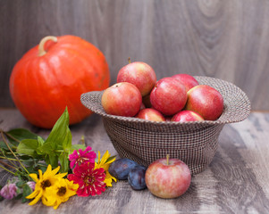 Red apples on a table. Hat with apples. Flower on a table. Wooden background with copy space