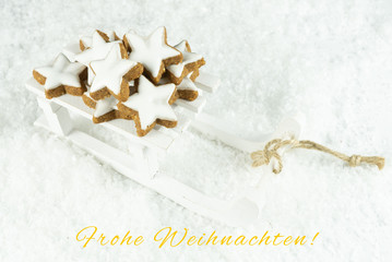Obraz na płótnie Canvas Sleigh with delicious Christmas cookies in the snow, card with the German words for merry Christmas