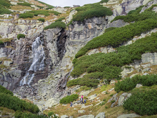 Skok waterfall High Tatras mountain with relaxing tourist people and hikers, summer sunny day, Strbske Pleso, Slovakia © Kristyna