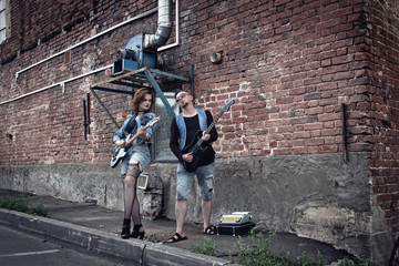Fototapeta na wymiar Girl and guy punks play on guitars