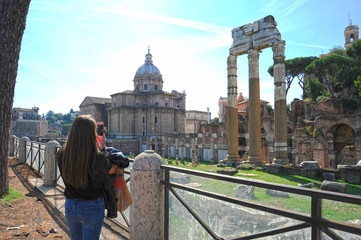 Young woman take photo with smartphone to the Imperial forums (Fori Imperiali) in Rome.