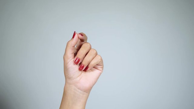 Closeup view of adult female hand raising up as if holding something virtual and invisible isolated on light background. Fingernails with beautiful red shiny manicure with modern gel polish paint. 4k