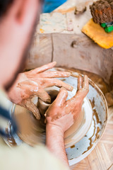 Professions and Craftmanship Concepts. Man Working with Clay on Potter's Wheel Inside of Workshop.