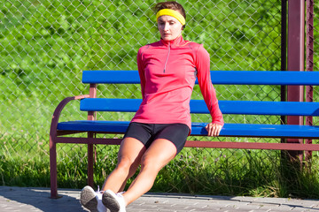 Sport Concepts. Full Length Portrait of Concentrated Caucasian Sportswoman in Outdoor Outfit Doing Push-Ups Near Bench Outside. Listening to Music in Headphones