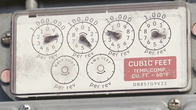 Mechanical gas meter dials measuring cubic feet in operation
