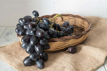 grappolo uva nera pizzutella in cestino rustico su iuta e sfondo bianco