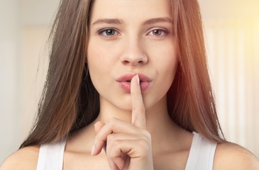 Fototapeta premium Young woman showing mute sign with her finger