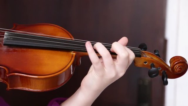 A close up shot of a young girl  practices her violin in classroom