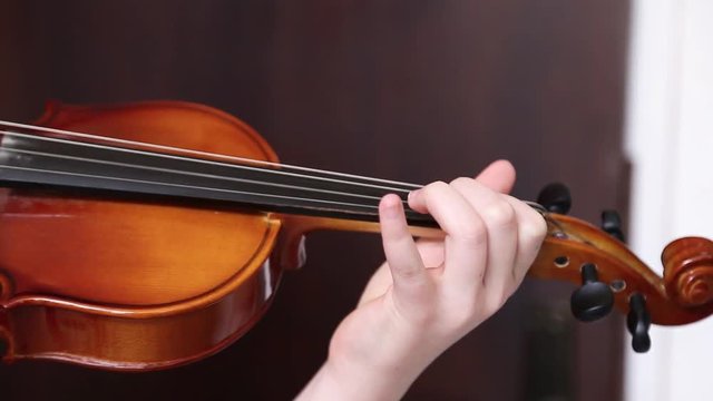 A close up shot of a young girl  practices her violin in classroom