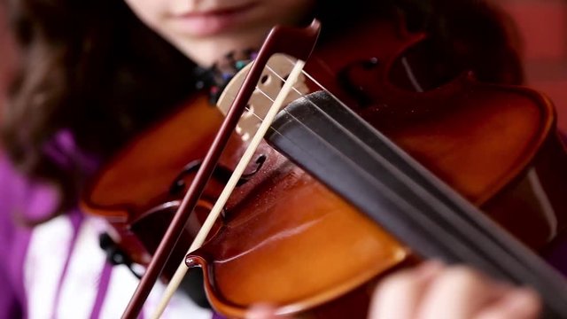 A close up shot of a young girl  practices her violin in classroom