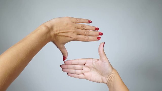 Closeup view of two female hands making square with both palms. Red fingernails. Point of view 4k video footage with copy space in middle of frame. Planning future and searching main point concept.