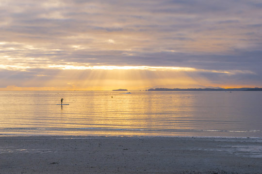 Landscape Scenery of Takapuna Beach Auckland, New Zealand; Sunrise time some people are enjoying paddle-boarding 