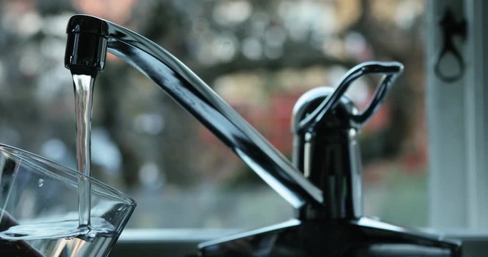 Person filling a glass of water.  Close up, dolly used for camera movement.