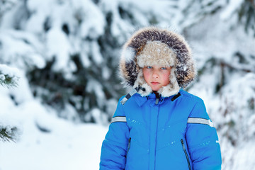 Fototapeta na wymiar Cute little boy wearing warm clothes playing on winter forest