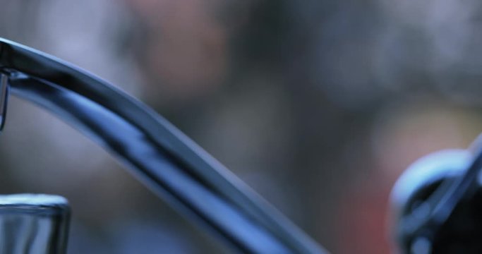 Glass under kitchen faucet is overflowing. Close up, dolly used for camera movement. 4K.