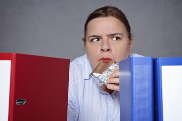 femme frustrée mangeant du chocolat au bureau